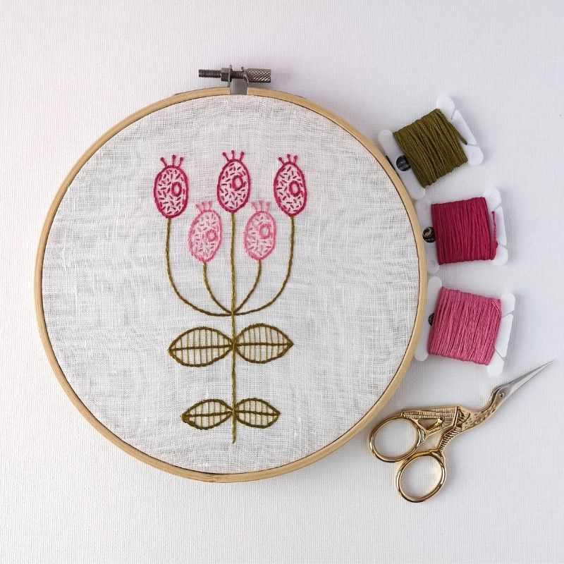 Pink modern flower embroidery in a hoop with colored floss and scissors